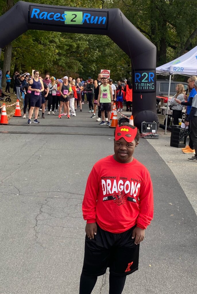 Bryan is dressed as a superhero wearing red near the start of the 5K running event.