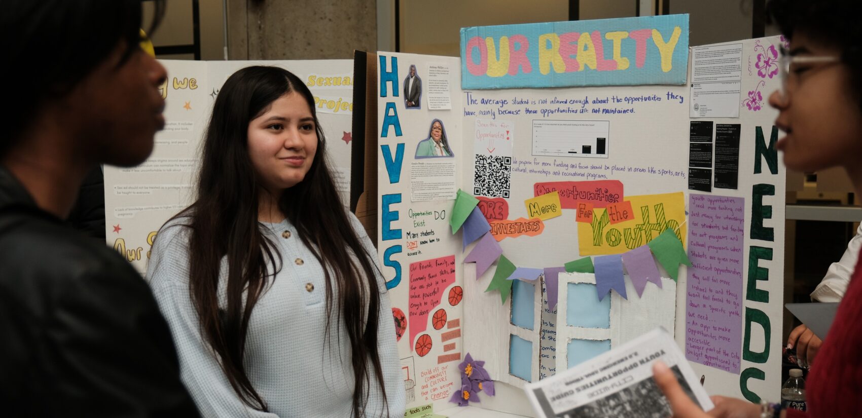 students at the Voter Education Summit next to a poster