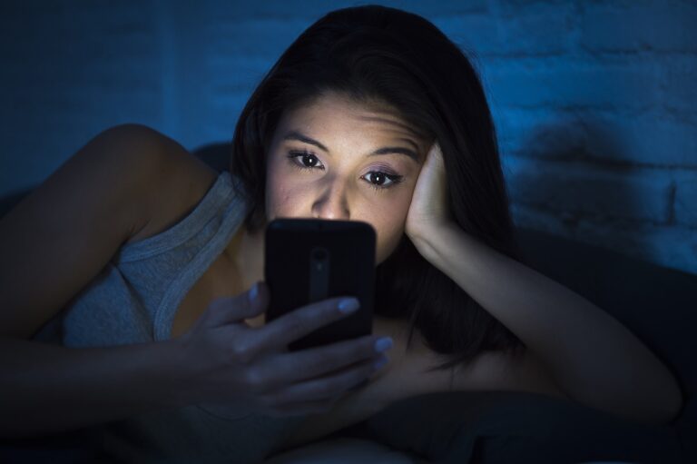 A young woman is using her smartphone at night.