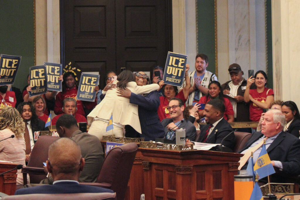 ice-out-vote-e-neil-2026-04-23-9 Rue Landau and Kendra Brooks hugging in Council chambers after the vote