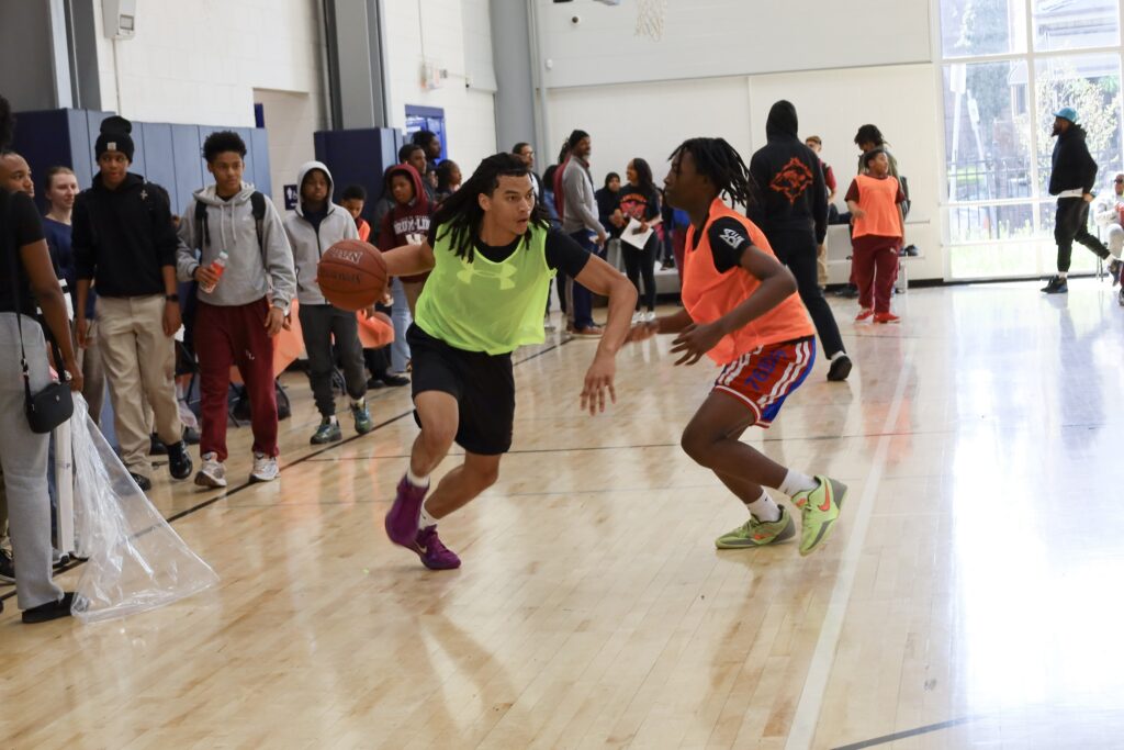 One student drives to the basket with another student defending them.
