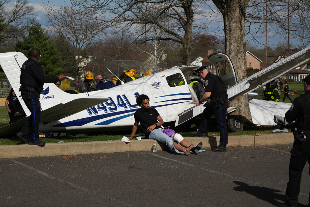 A passenger sits besides the aircraft at the scene after a small airplane made a crash landing