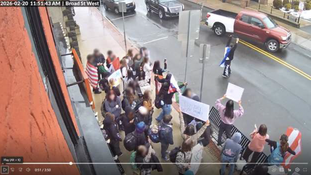 quakertown-protest-police-2026-04-17 Surveillance photo of protesters blocking an entire sidewalk and one person in the middle of the street.