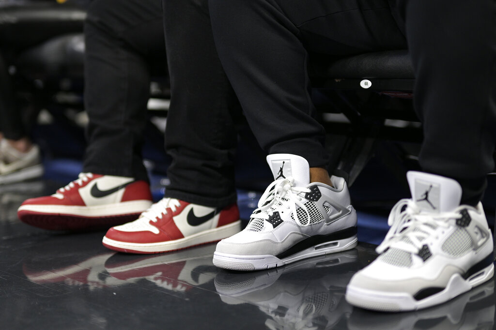 Spectators wears Nike Air Jordan shoes while sitting in court side seats during the second half of an NBA basketball game