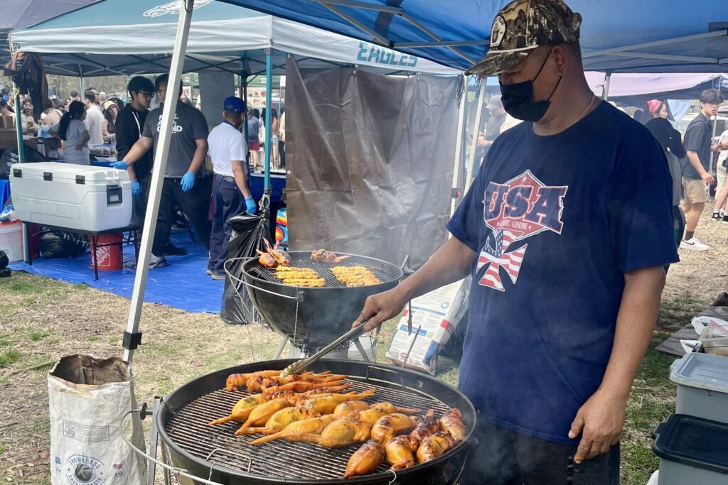 A vendor grills skewers of different meats
