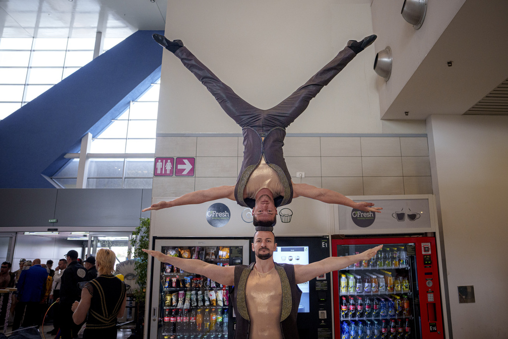 A circus artist balances another circus artist on their head
