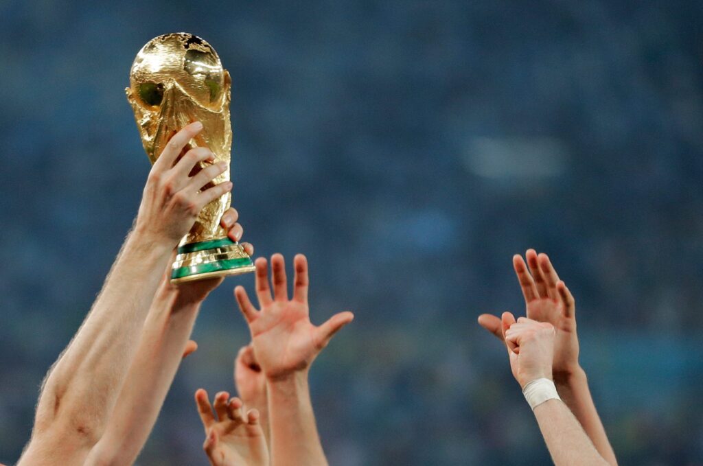hands reaching up to touch the world cup trophy as one person holds it up