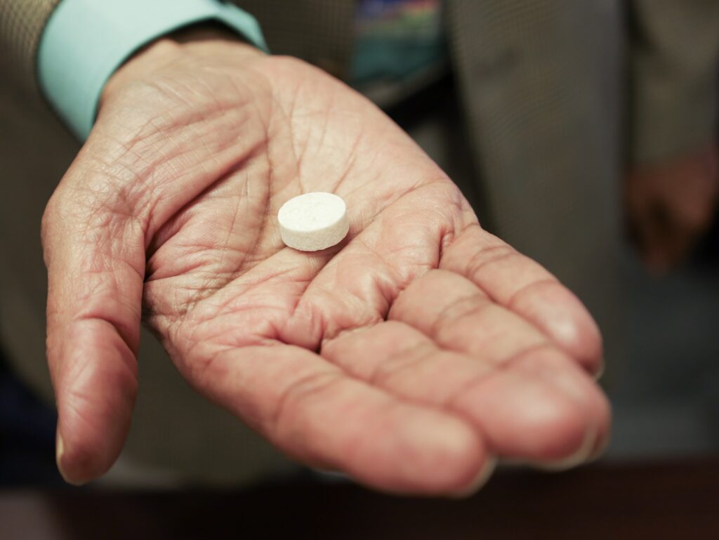 A small pill sits in the middle of a person's outstretched hand.