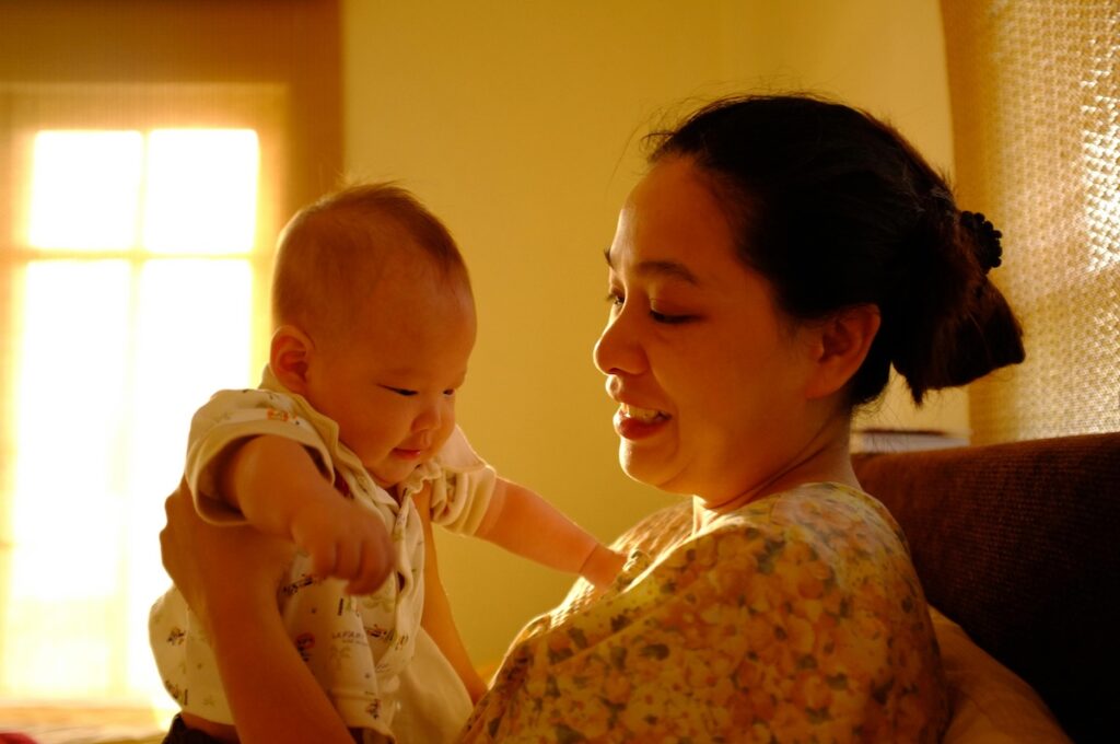 pexels-wutthichai-charoenburi-553075115-20030664 A mother is smiling while holding a newborn baby.