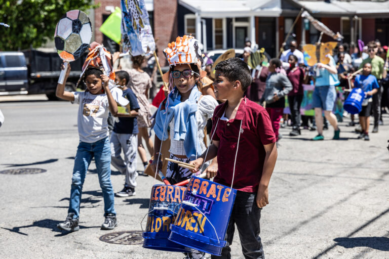 School children have a parade with their large puppets and signs.