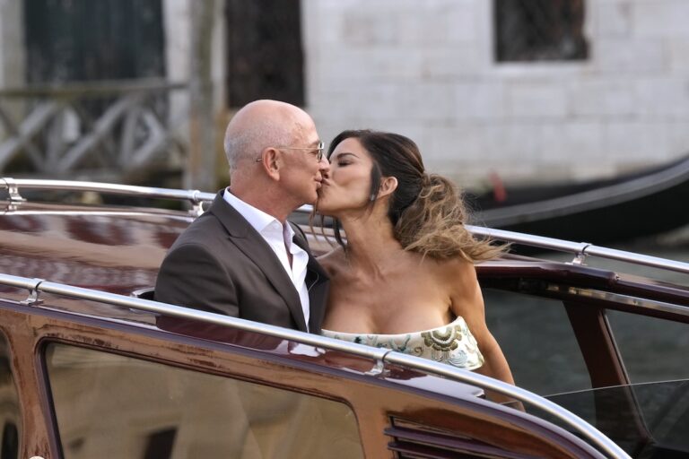 Jeff Bezos, center left, and Lauren Sanchez, center right, kiss as they leave a hotel for their pre wedding reception, in Venice, Italy, Thursday, June 26, 2025. (AP Photo/Luca Bruno)