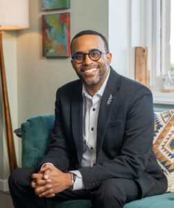 Neal Holmes is posing for a photo in his office.