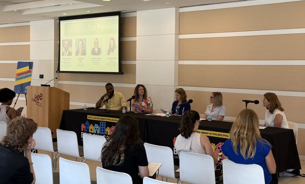 Panelists sit at a table with microphones for the panel discussion
