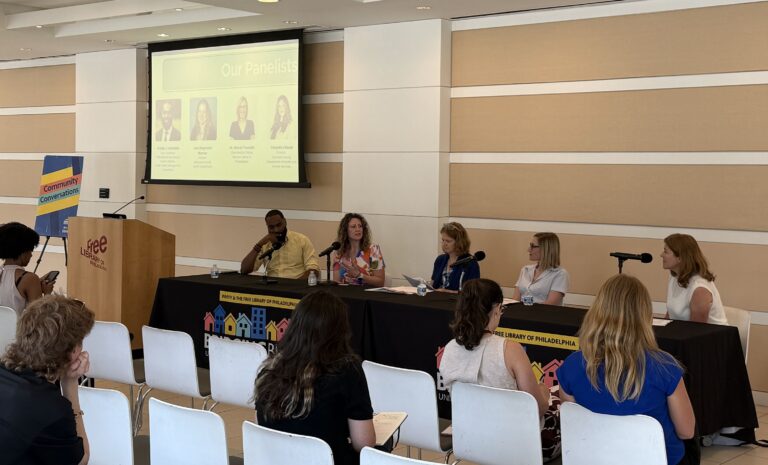 Panelists sit at a table with microphones for the panel discussion
