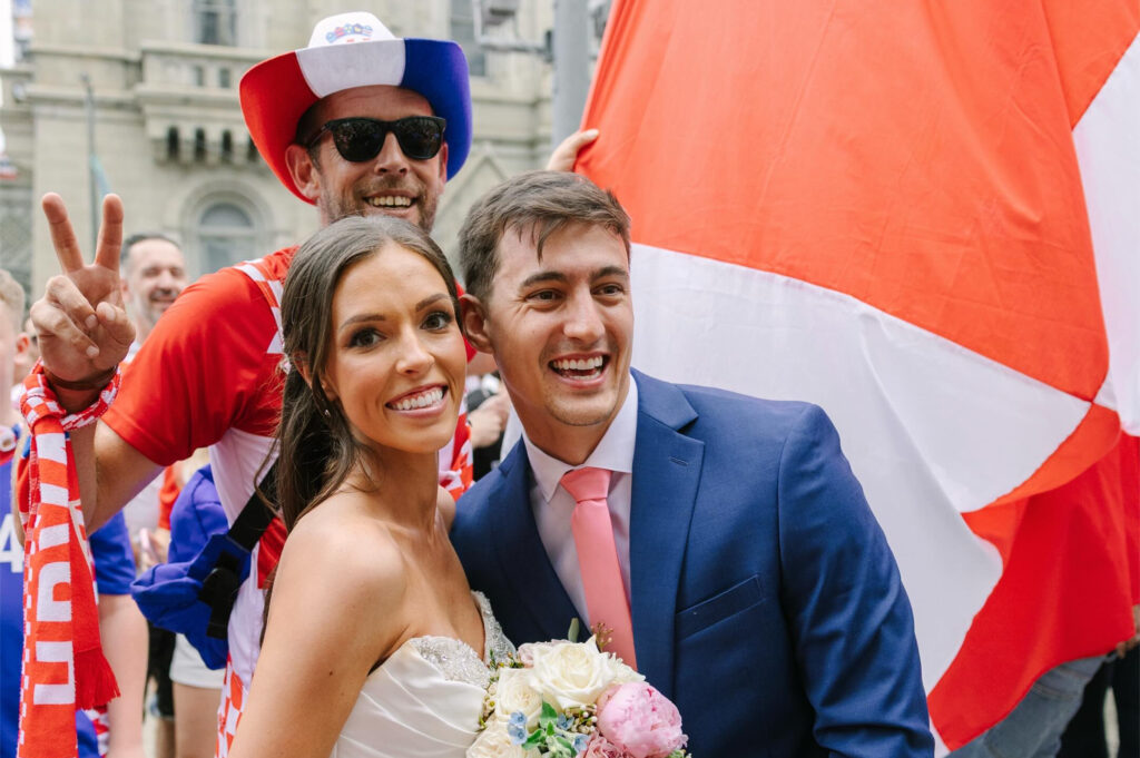 croatia-wedding-bp-2026-06-29 Newlyweds posing for a photo while a Croatia fan crashes the picture behind them.