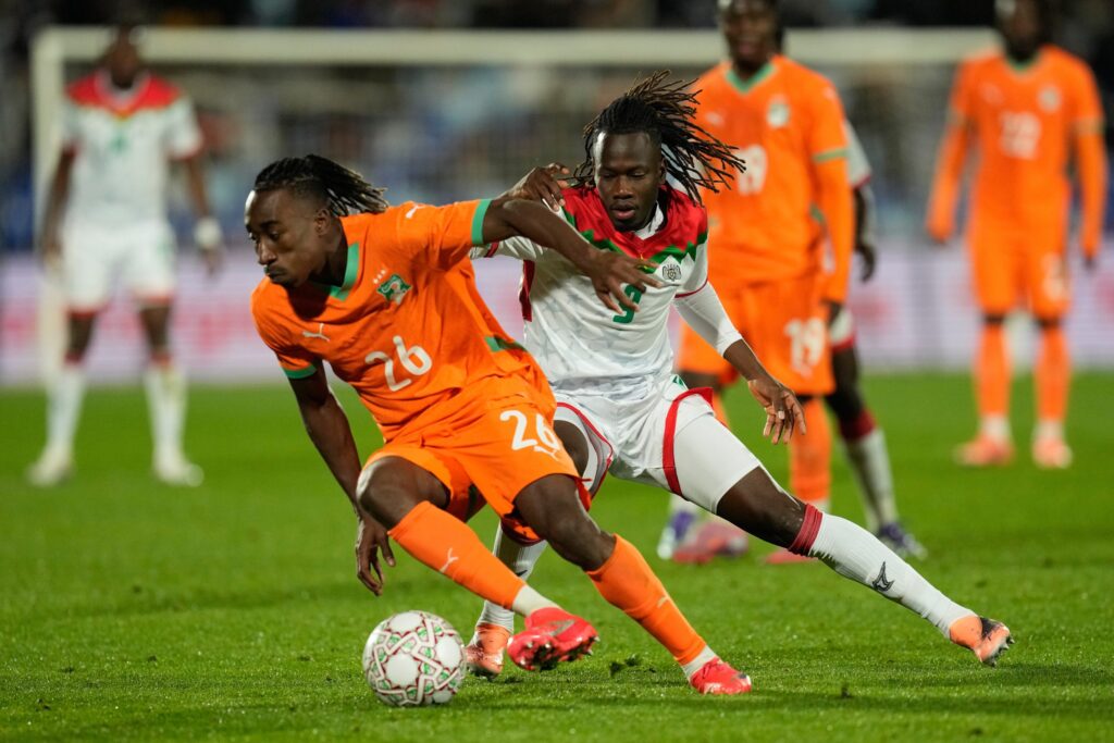 fifa-ivory-coast-ap-2026-06-04 Yan Diomande dribbles the ball while Issa Kabore challenges from behind during a match.