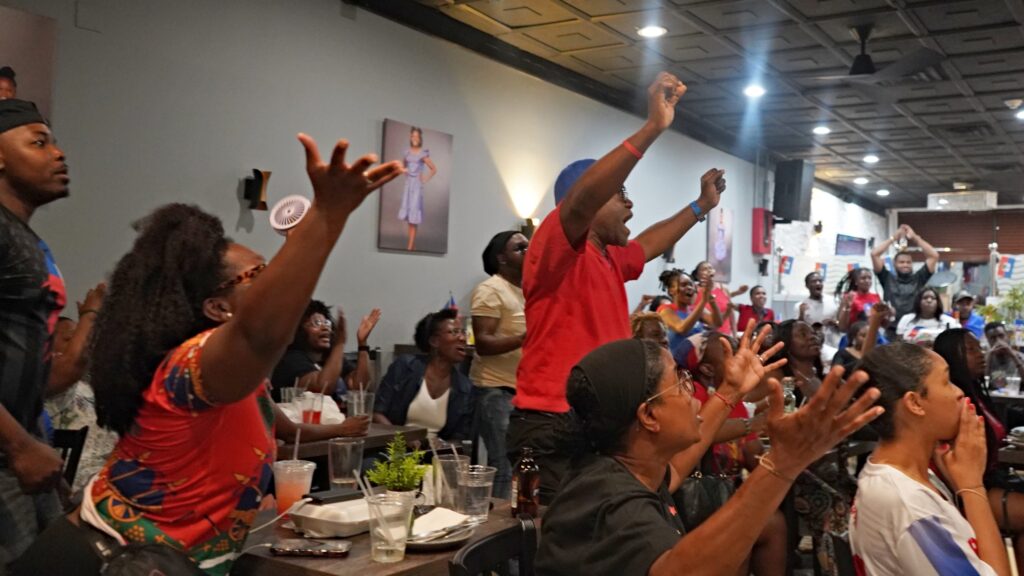 Haiti fans raise their arms in disbelief at a missed goal during the game.