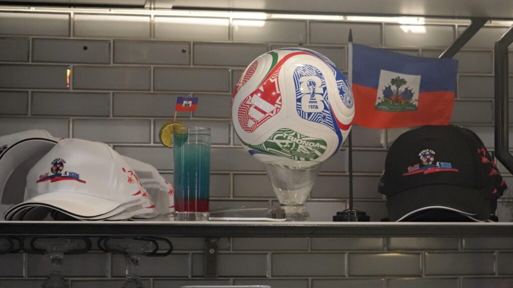 A soccer ball, mini flag and hats are on display on a shelf.