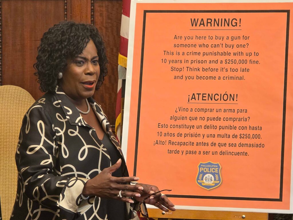 mayor-cherelle-parker-gun-straw-purchase-regulations-2025-09-08 Cherelle Parker speaking at a press conference in front of a poster outlining new gun regulations.