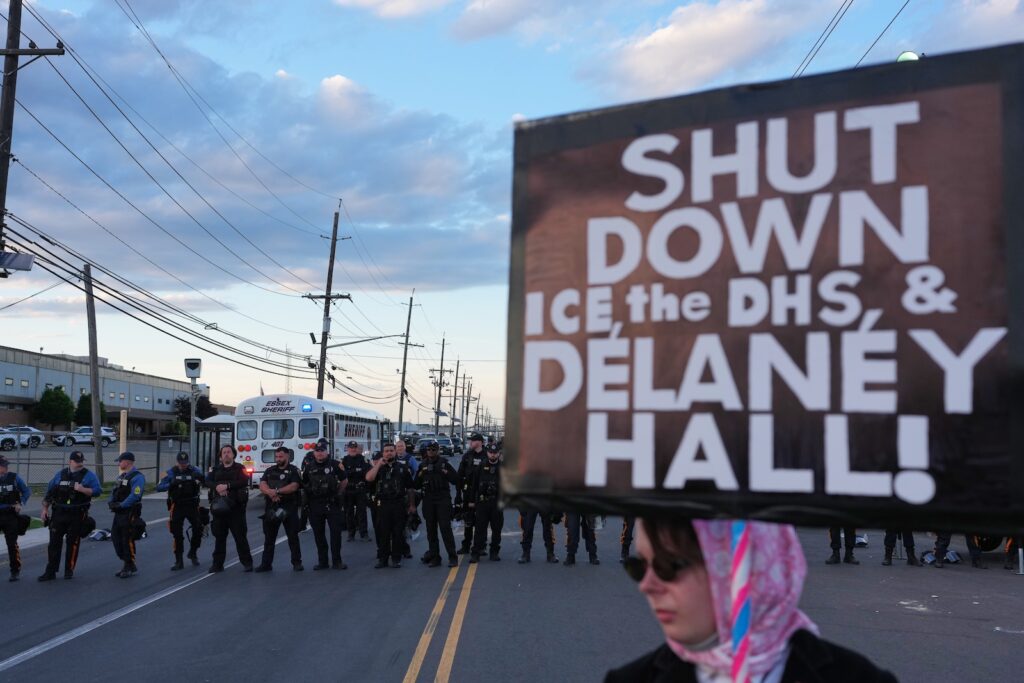 Immigration Protests New Jersey A protester holds a sign that says, ''Shut down ICE, the DHS, and Delaney Hall!'' as law enforcement officers stand outside Delaney Hall detention center Sunday, May 31, 2026, in Newark, N.J.