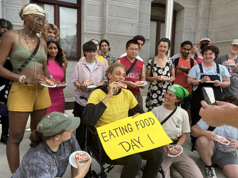 A person in a wheelchair eat a piece of bread with the words 