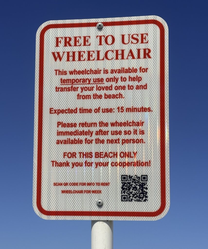 A sign posted at the beach advertises a free to use wheelchair.