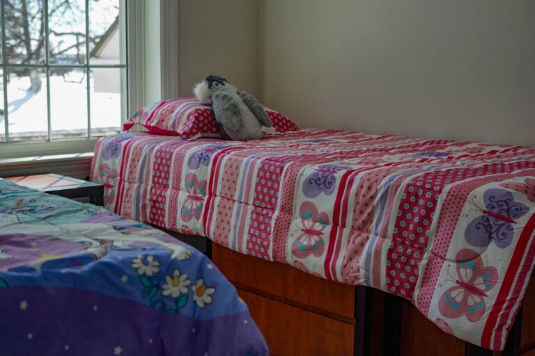 2 children's beds are seen in a bedroom.