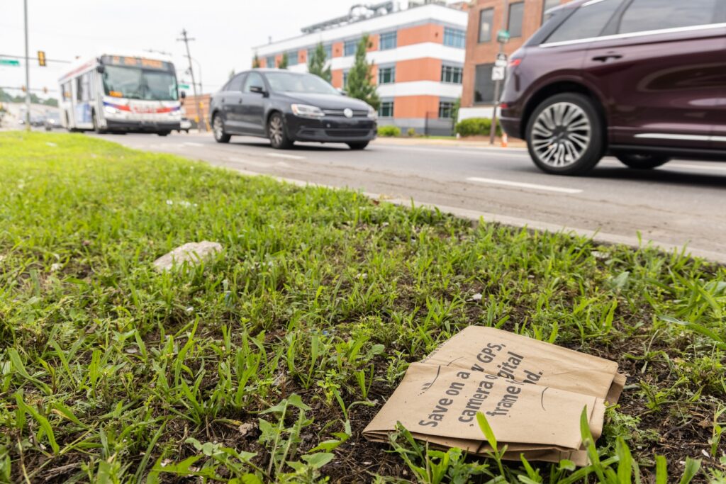 A paper bag littered by the road in South Philadelphia. (Kimberly Paynter/WHYY) A paper bag is discarded next to a busy road.