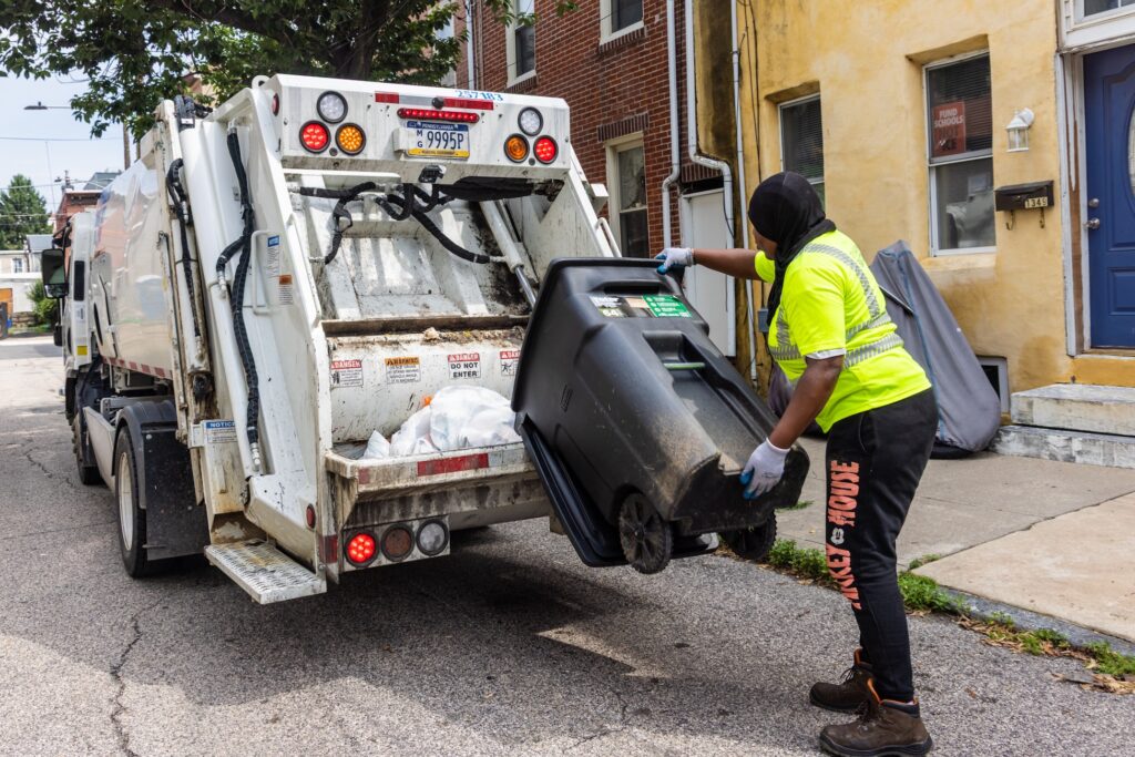 07 10 2026 k paynter trash collectiong truck and sanitation philadelphia -2 Sanitation workers load bags of trash into the back of the truck.