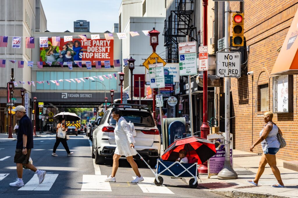 People walking across a busy intersection in Philly's Chinatown neighborhood