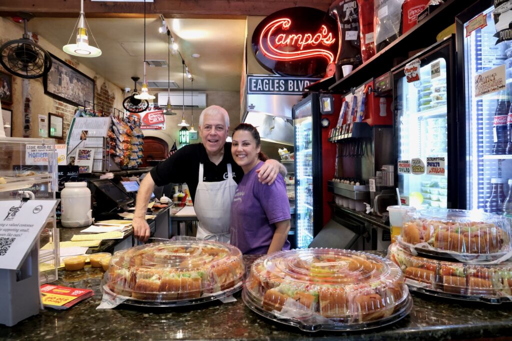 2026 06 16-e lee-michael campo mia campo-philadelphia old city campos deli-father daughter Michael and Mia Campo posing for a photo behind the counter at Campo's.