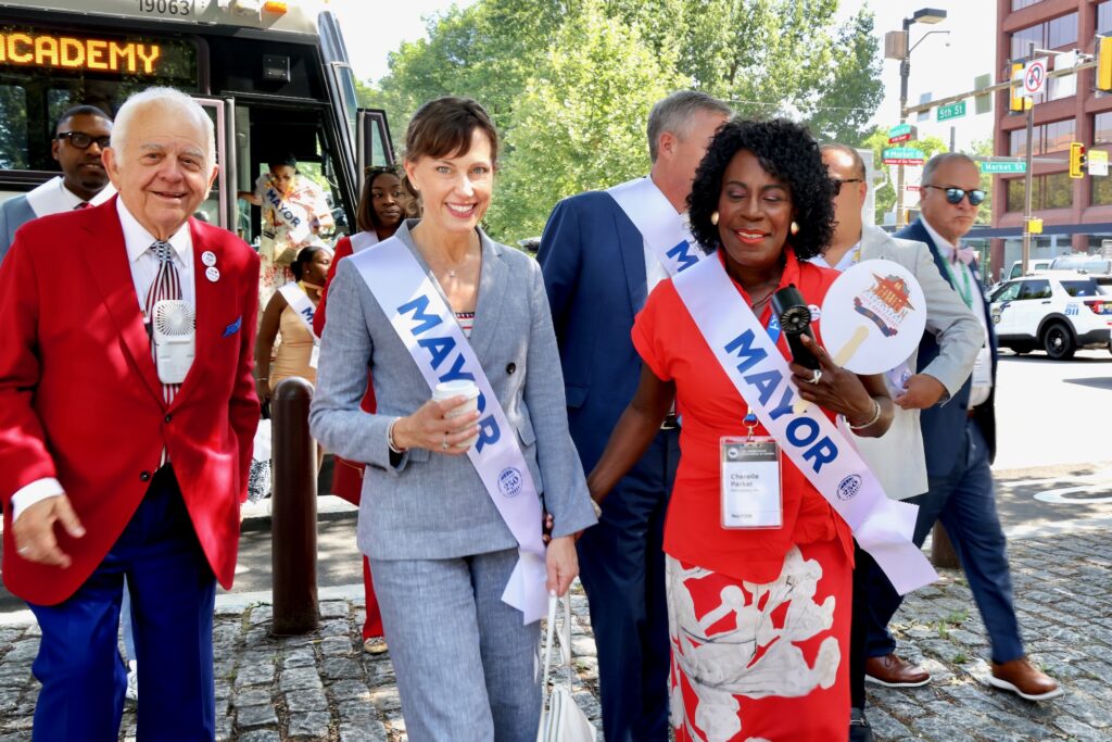 Members of the U.S. Conference of Mayors climb off their buses at 5th and Arch streets