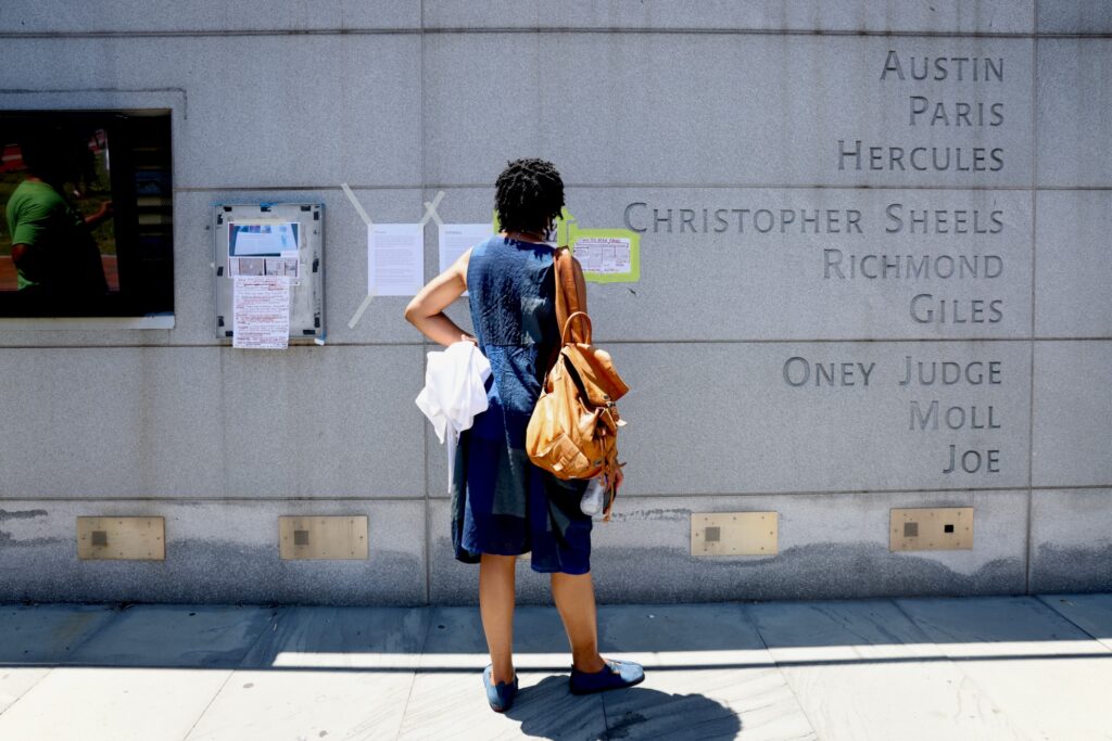 A woman stops at the wall inscribed with the names of nine people enslaved by George Washington