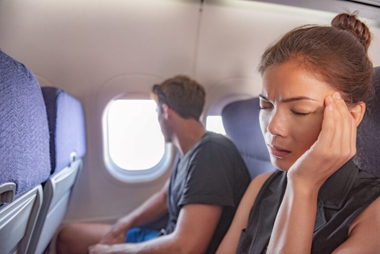 Sick woman on airplane with headache.