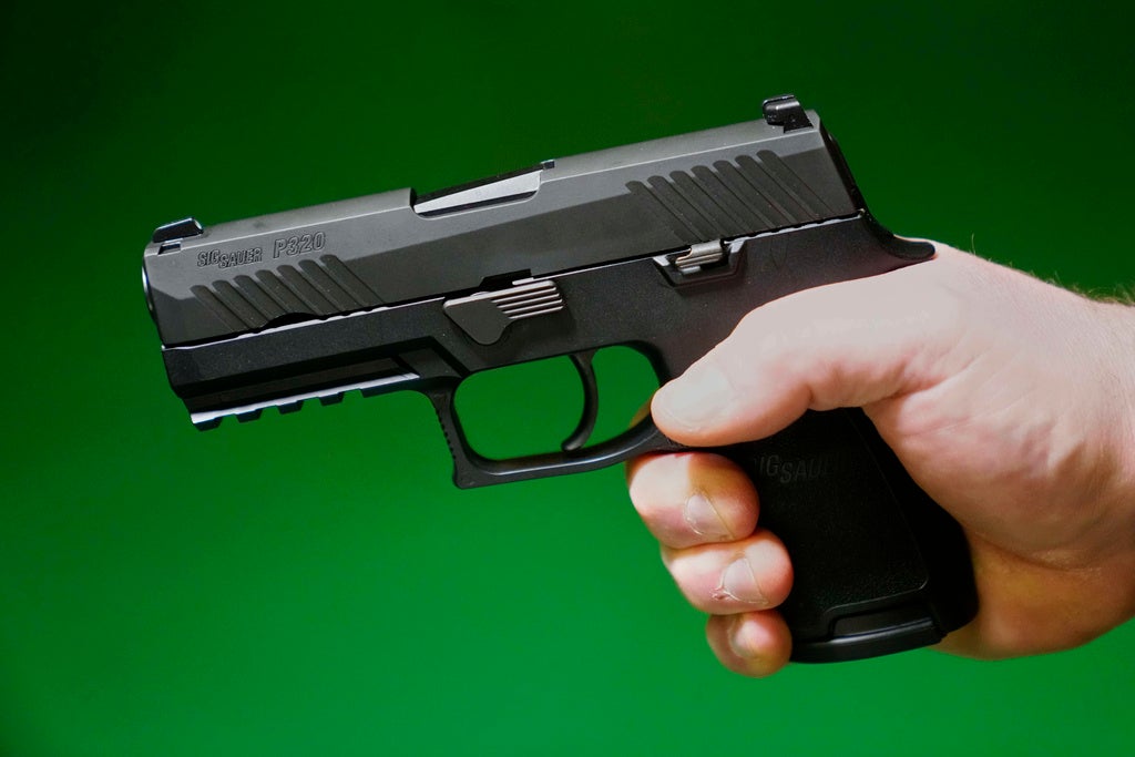 Un propietario de una armería de Maine sostiene una pistola Sig Sauer P320