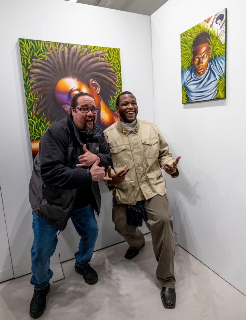 Alain Jean-Baptiste poses with his teacher at a gallery featuring his paintings.