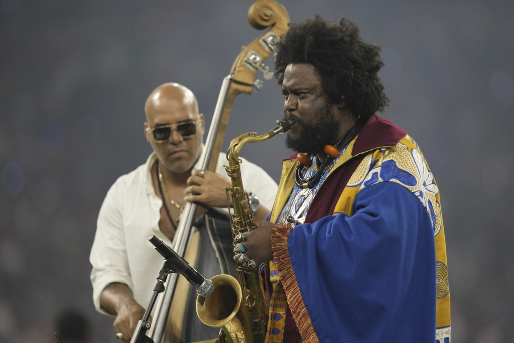 Kamasi Washington performs saxophone on a stage