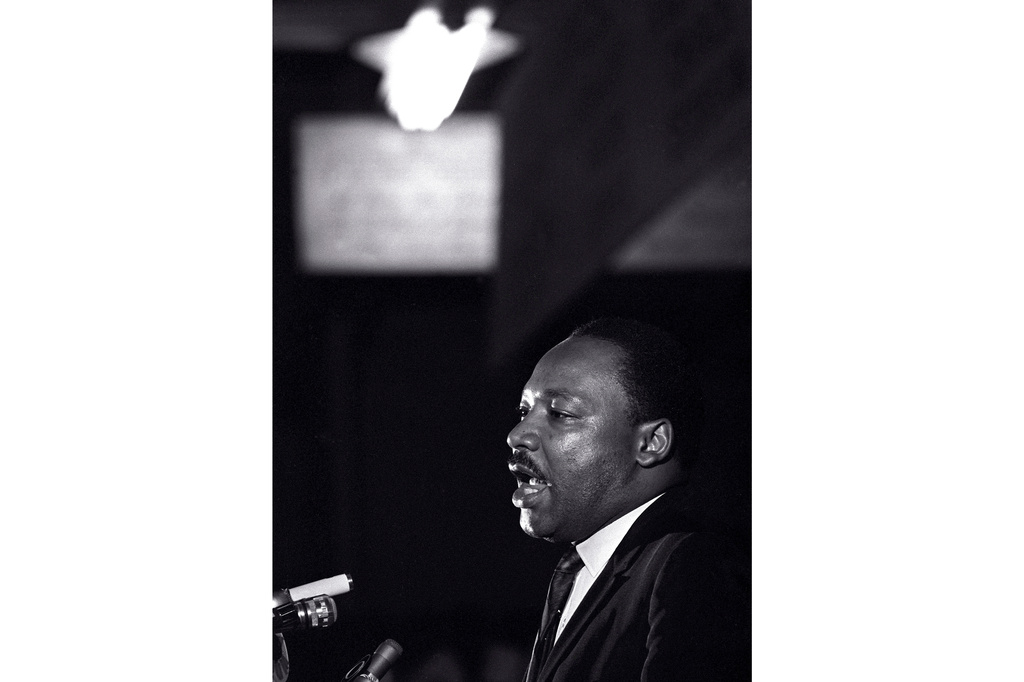Martin Luther King Jr. speaks into a microphone in a black and white photo
