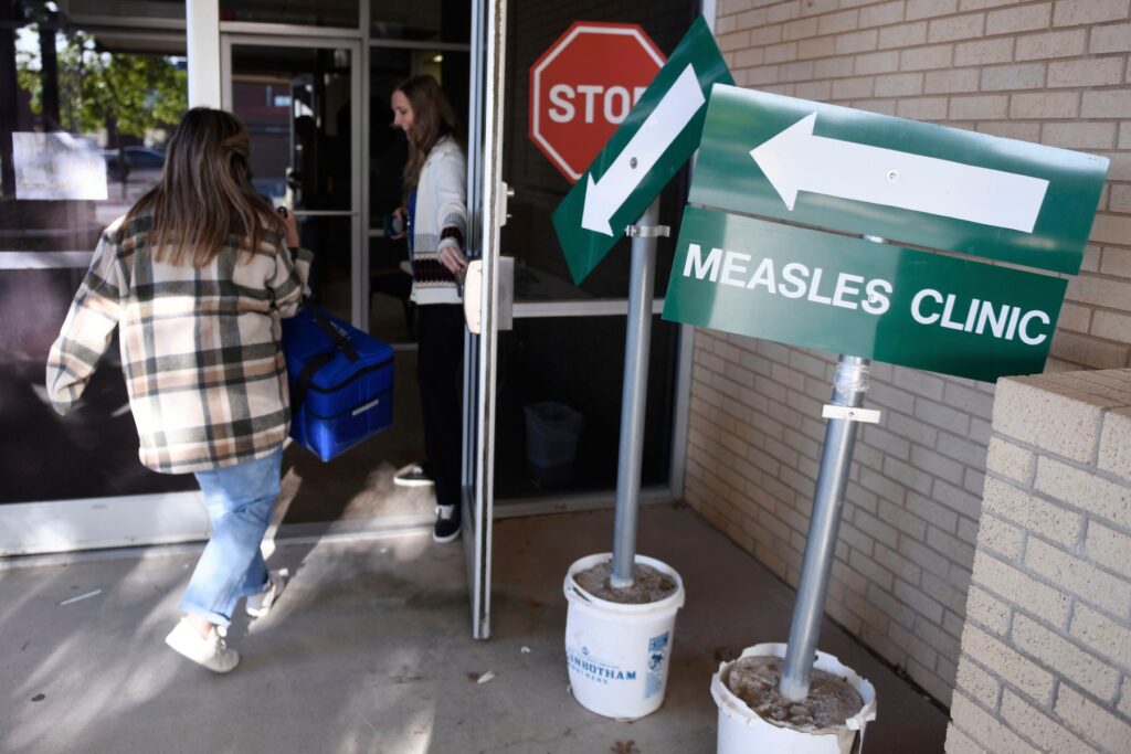 Measles FILE - Health department staff members enter the Andrews County Health Department measles clinic