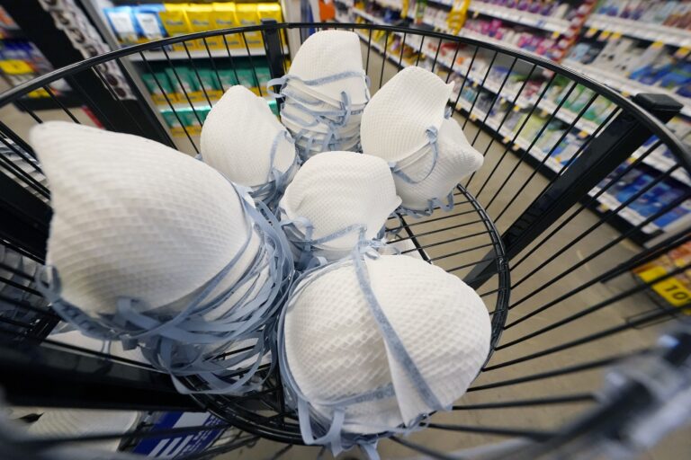 FILE - A product stall filled with free N95 respirator masks, provided by the U.S. Department of Health and Human Services, sits outside the pharmacy at this Jackson, Miss., Kroger grocery store, Wednesday, Feb. 2, 2022. (AP Photo/Rogelio V. Solis)