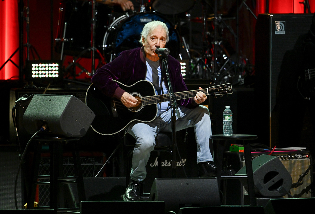Paul Simon plays guitar on stage