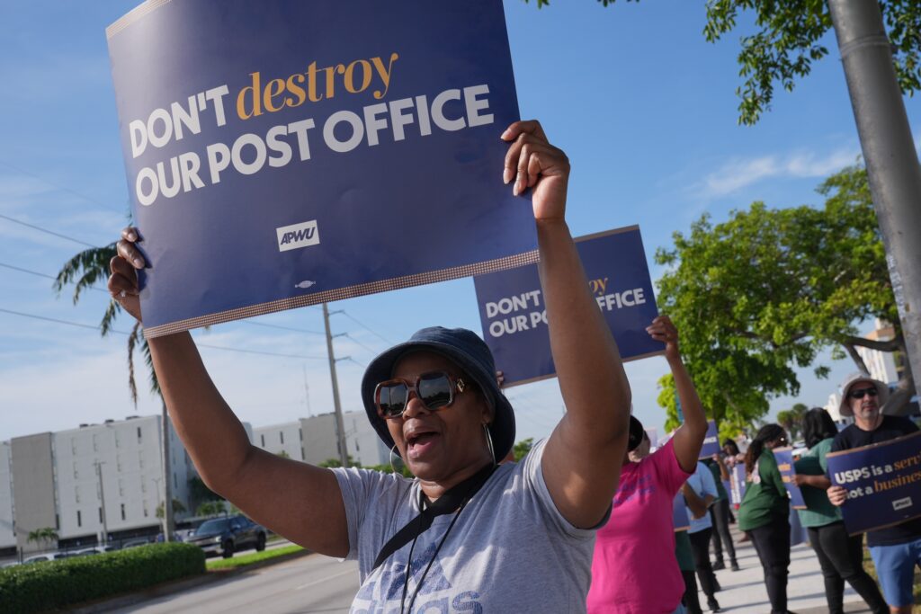 Election 2026 Postal Service Yvonne Daniels holding up a sign at a pro-USPS protest.