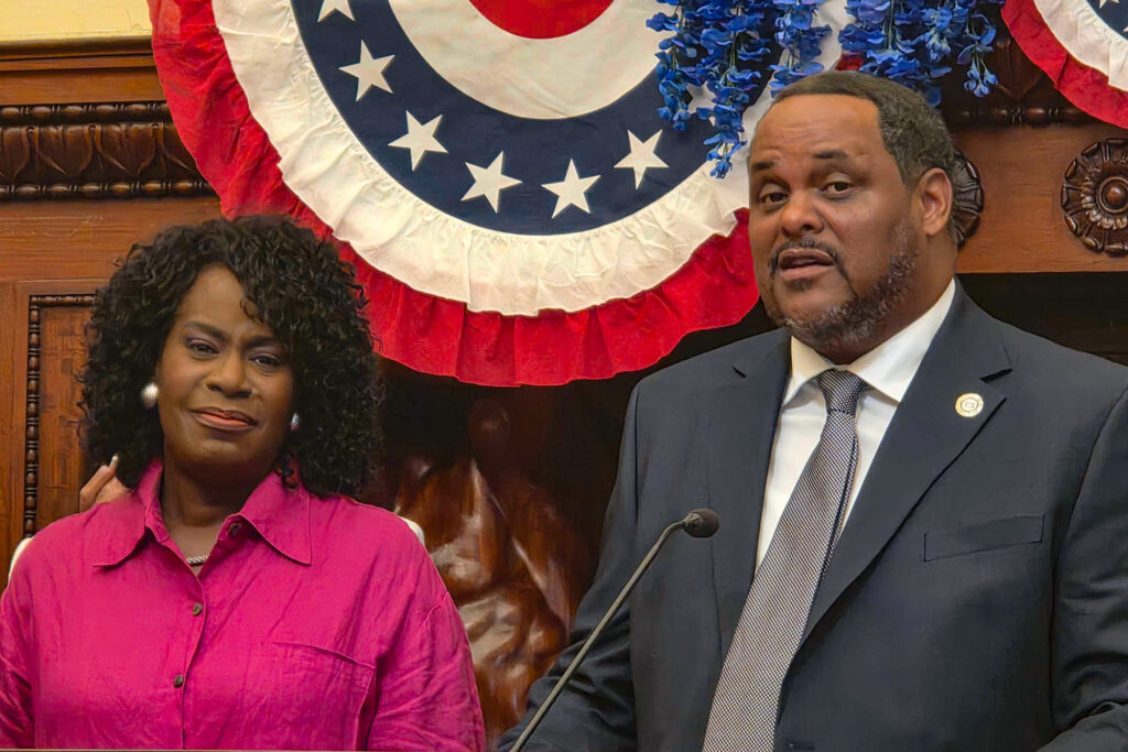 williams-parker-tmacdonald-2026-07-28 Carlton Williams speaking at a podium in City Hall, with Mayor Cherelle Parker standing beside him.