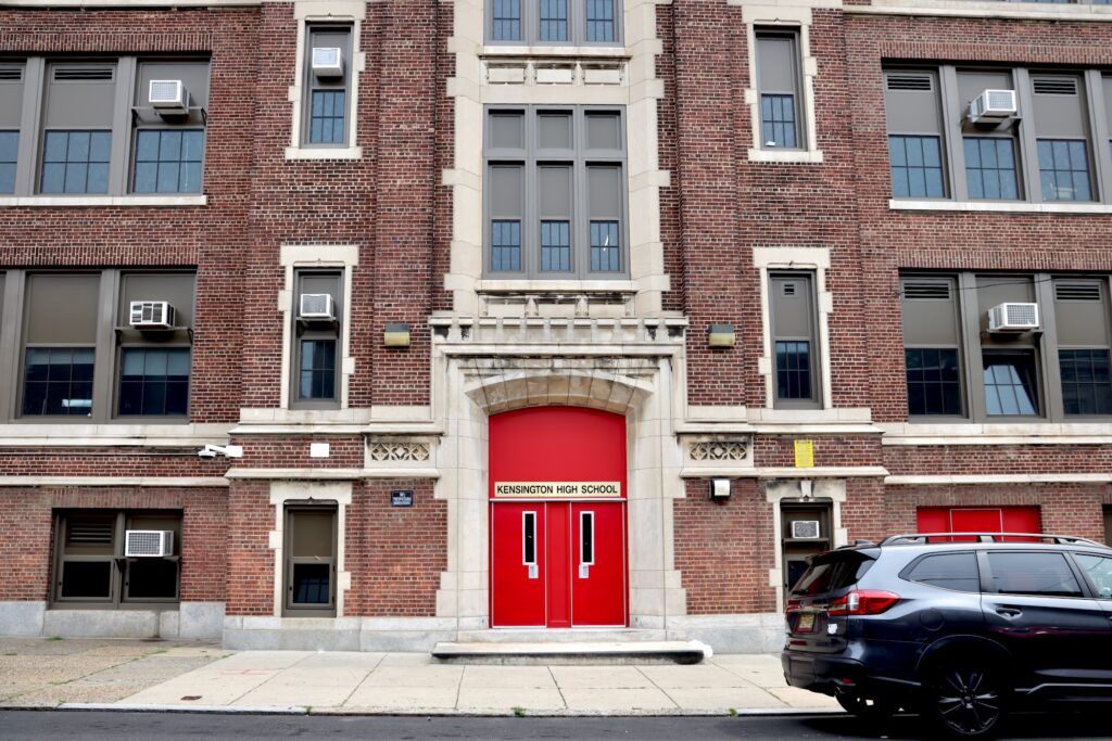20 08 14-e lee-philadelphia kensington high school-closing for asbestos red doors A sign above the bright red door marks the entrance to Kensington High School