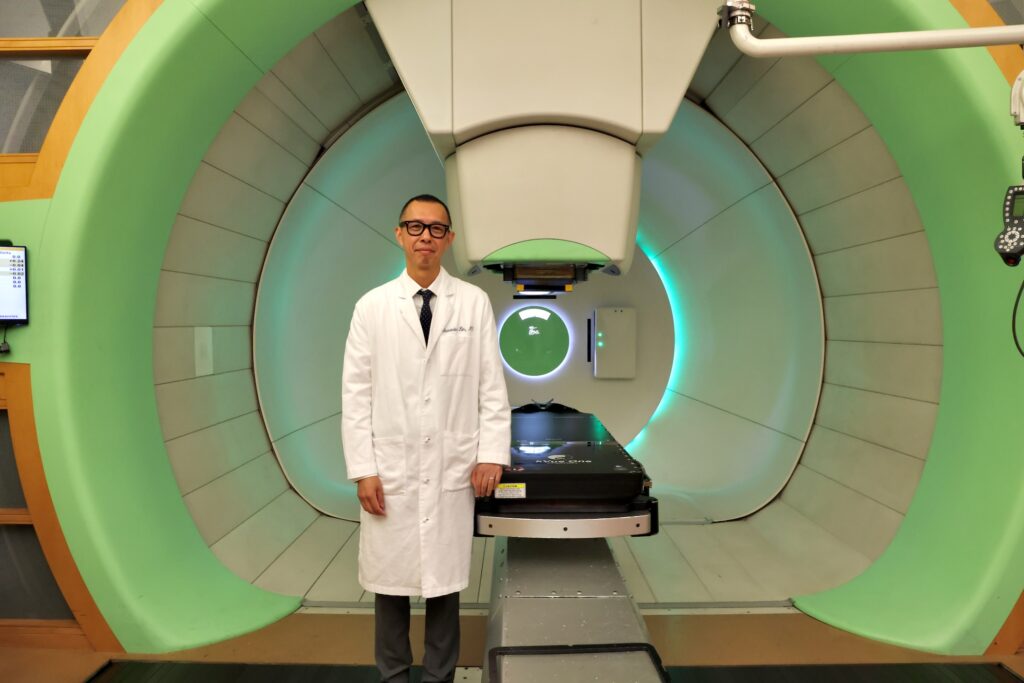 2026 08 26-e lee-alexander lin-philadelphia university of pennsylvania perelman center-flash proton therapy Alexander Lin smiles in front of the FLASH cancer-killing radiation therapy machine