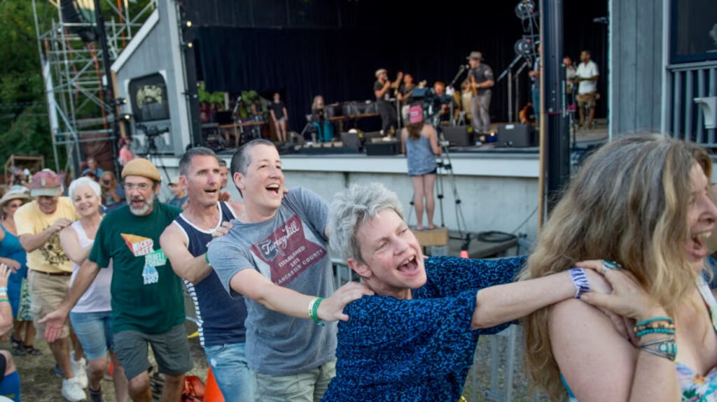 Folk-Fest-2017-22-file Audience members form a conga line while a band performs onstage