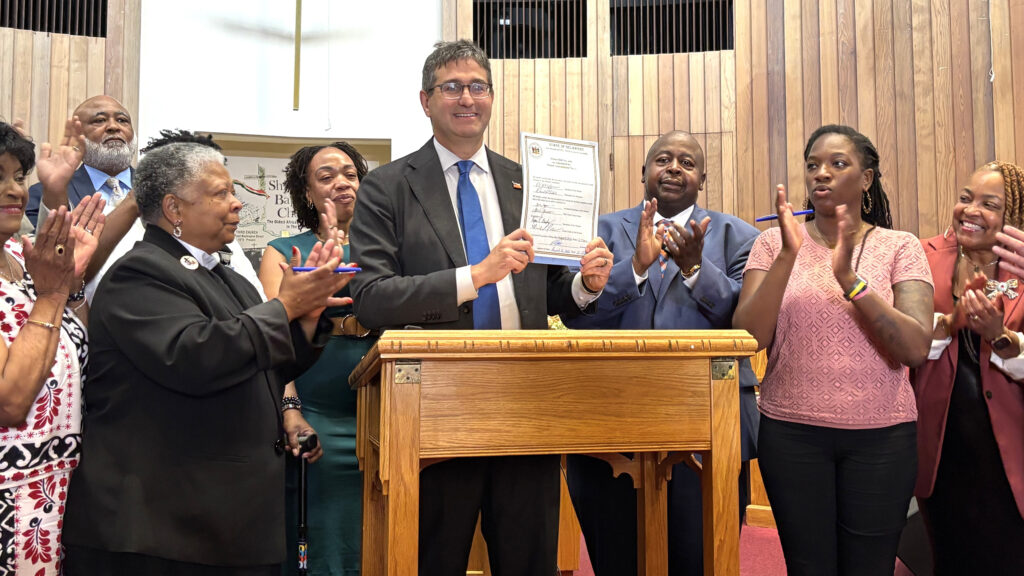 John Lewis signing copy Delaware Governor Matt Meyer and lawmakers celebrate the signing of a state Voting Rights Act, with Meyer holding the bill up