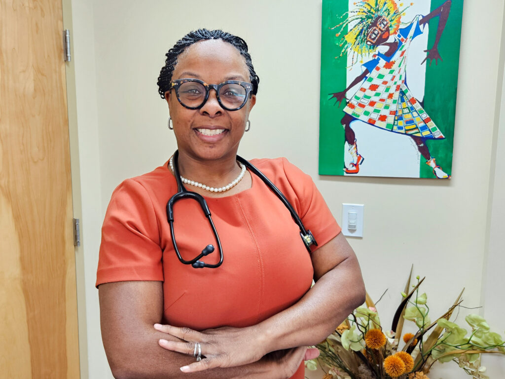 A woman doctor in red scrubs with a stethoscope around her neck