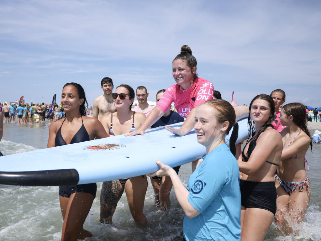 amanda-parezo-NL-080726-01 Amanda Parezo on a surfboard carried by friends