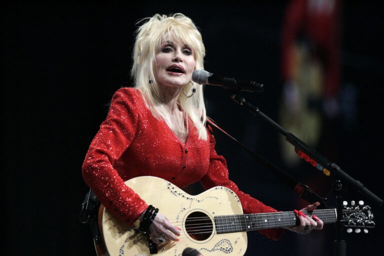 Dolly Parton is singing and playing guitar on stage in Detroit in 2009.